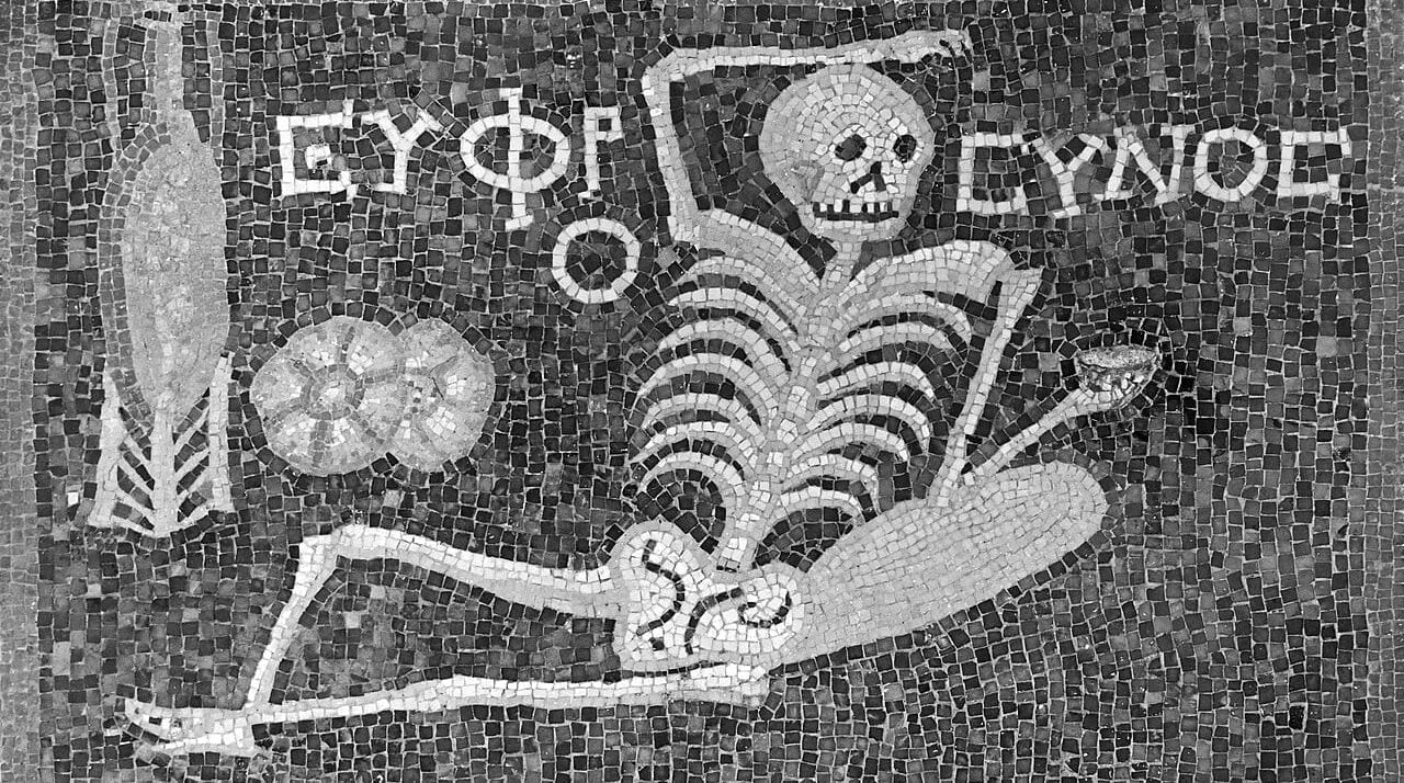The inscription mentions the male form of the Grace Euphrosyne, and that stands for, Be cheerful, enjoy your life. This 2,400 year old Roman mosaic depicts a skeleton lying down with a jorum in his hand, a wine pitcher and bread on the side. Hatay Archaeology Museum, Antakya, Turkey. 