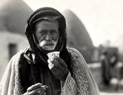 Photo post-card by V. Derounian,1930, of an inhabitant of a Beehive village in Aleppo's district in northern Syria.