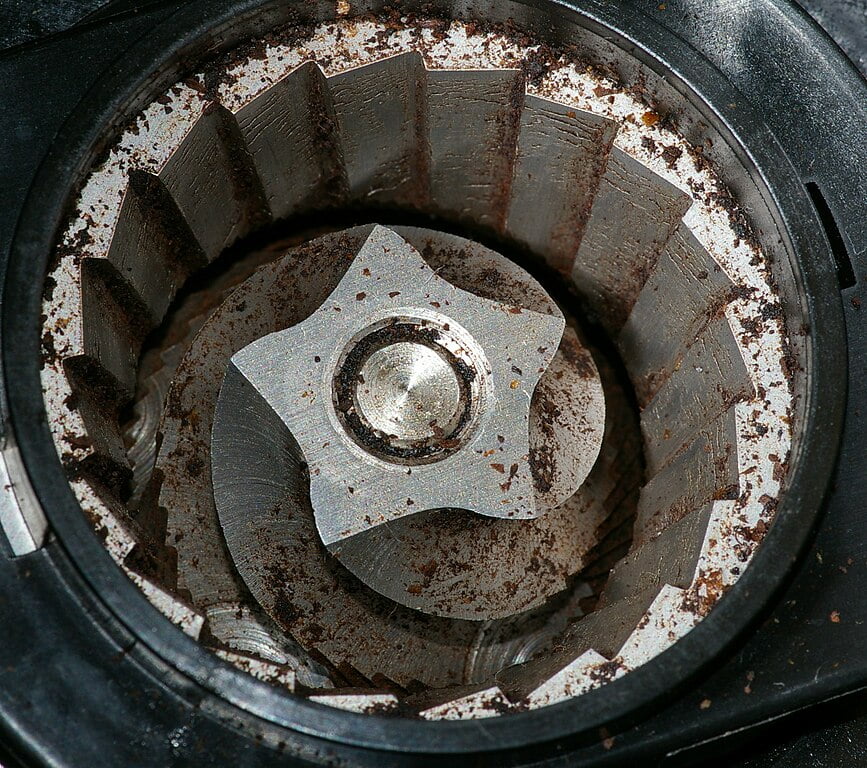 A detail view of a coffee burr grinder. The bean hopper, which would be immediately above this grinder, has been removed. Hustvedt C C A-S A 3.0